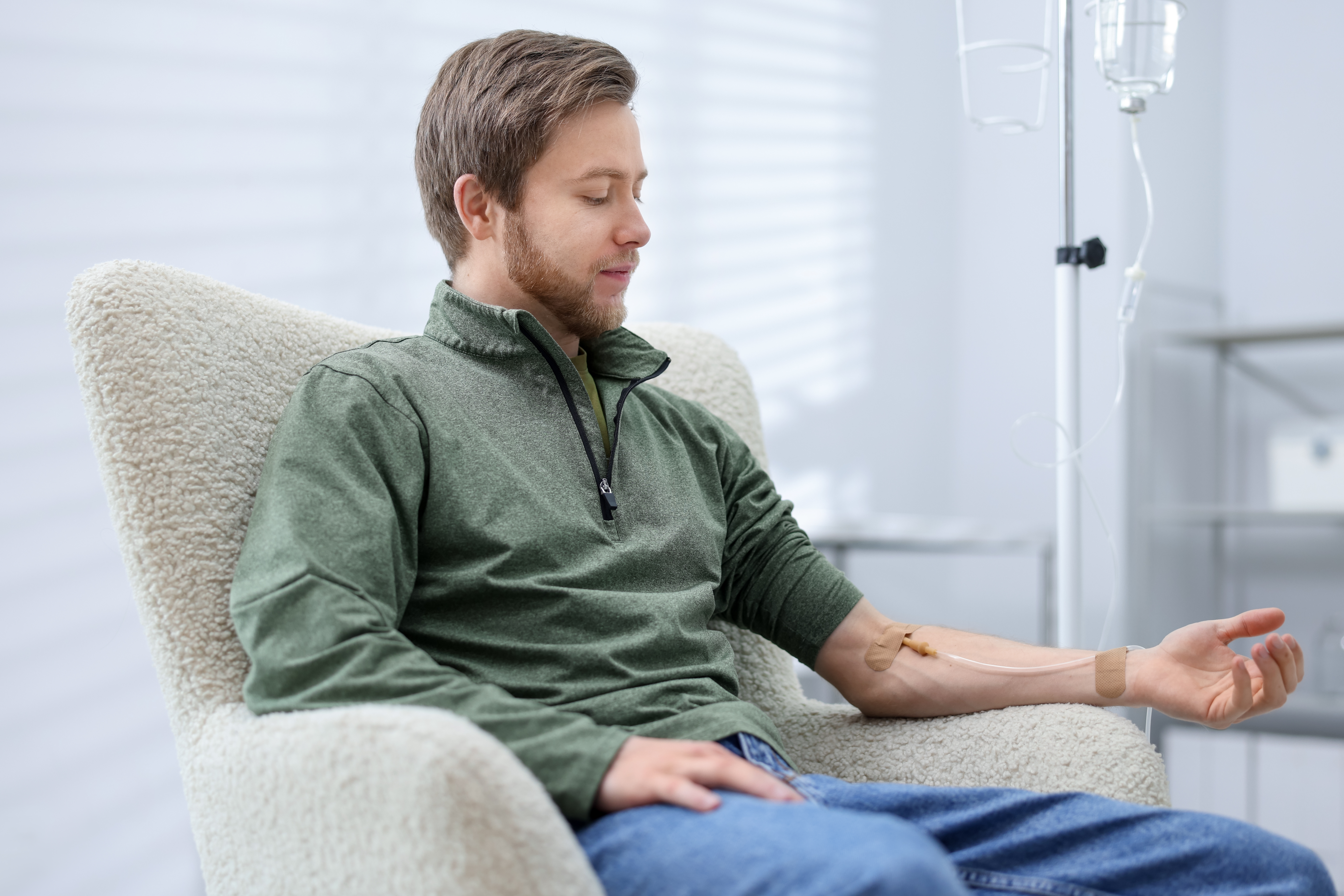 Young man relaxing in an armchair with an IV drip at a wellness clinic