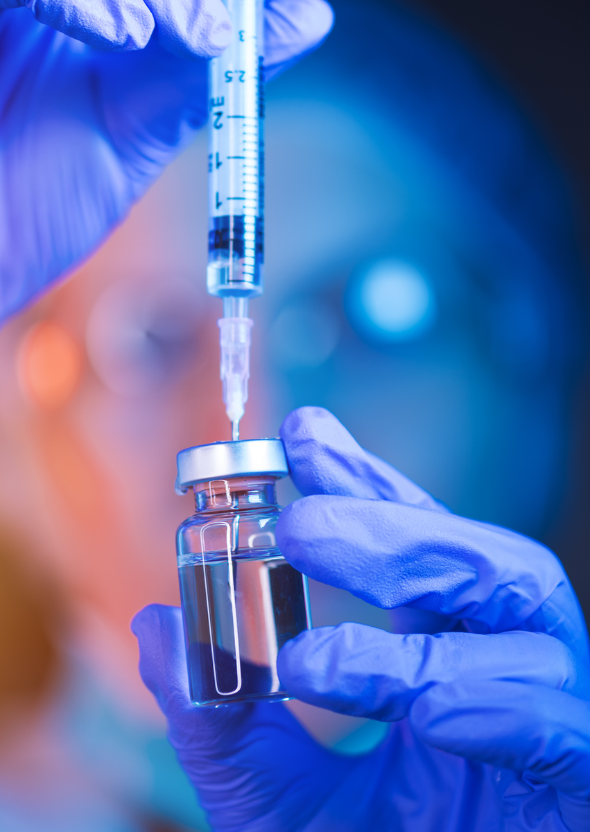 Gloved clinician drawing peptide medication from a vial with a syringe