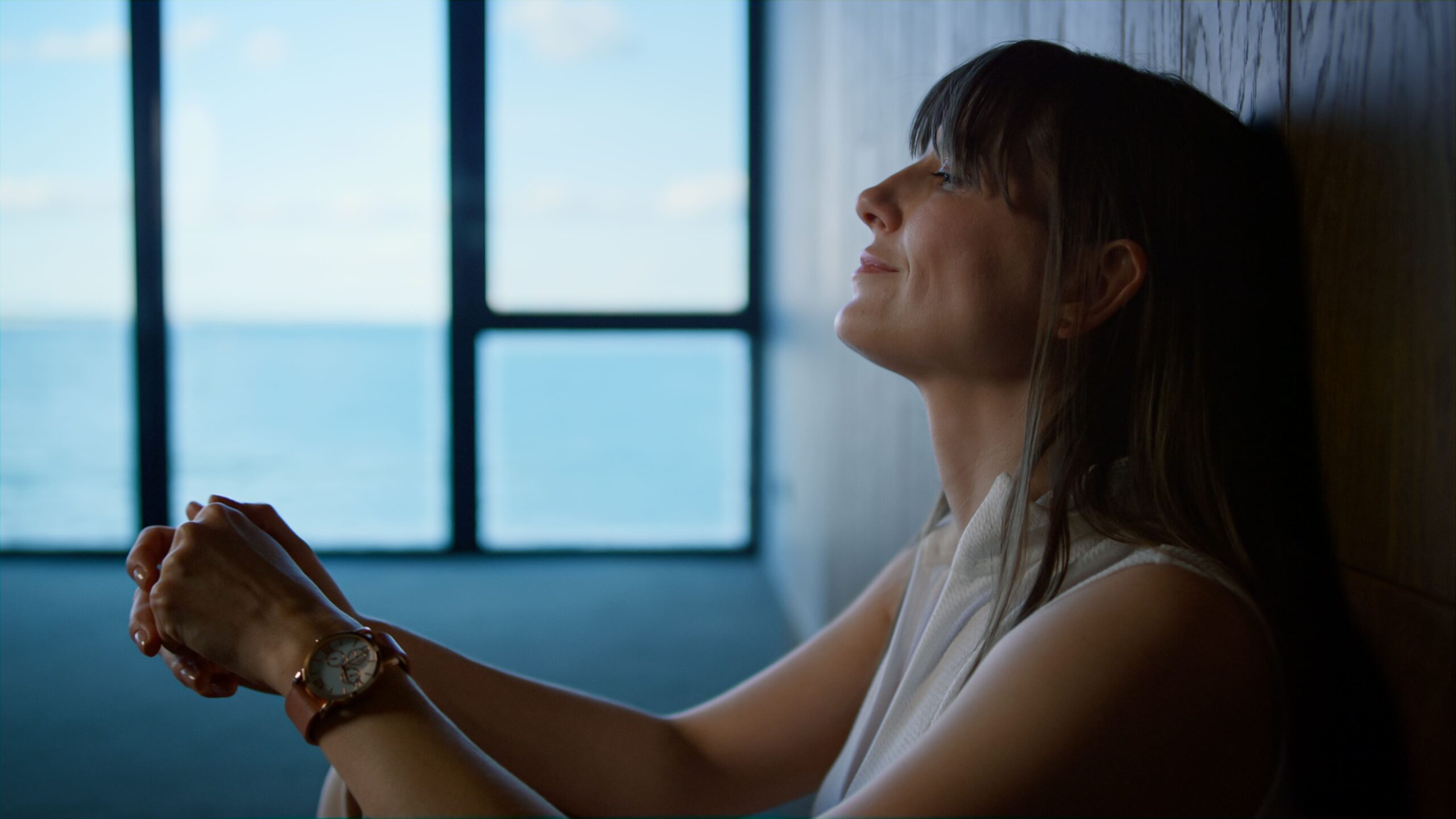 Thoughtful woman sitting by a window with an ocean view